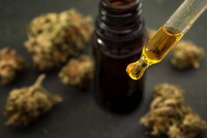 flacon d'huile de CBD sur une table en bois avec plantes vertes en arrière-plan